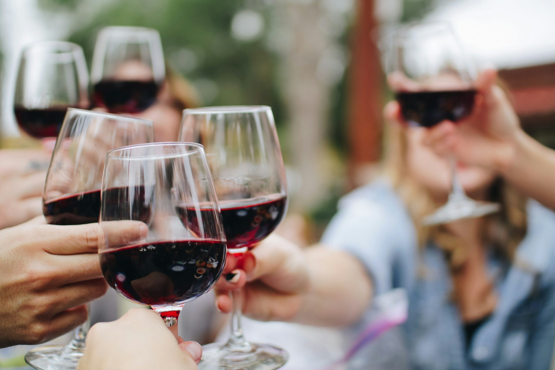 Friends clinking glasses of red wine together outdoors